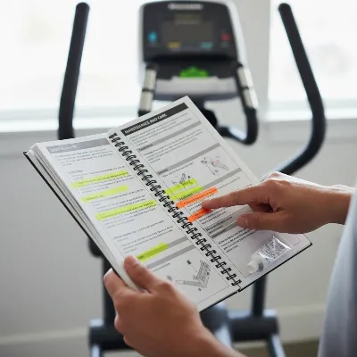 Hands holding an elliptical user manual open