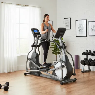 Sole E35 elliptical trainer positioned in a home gym setting with a user exercising